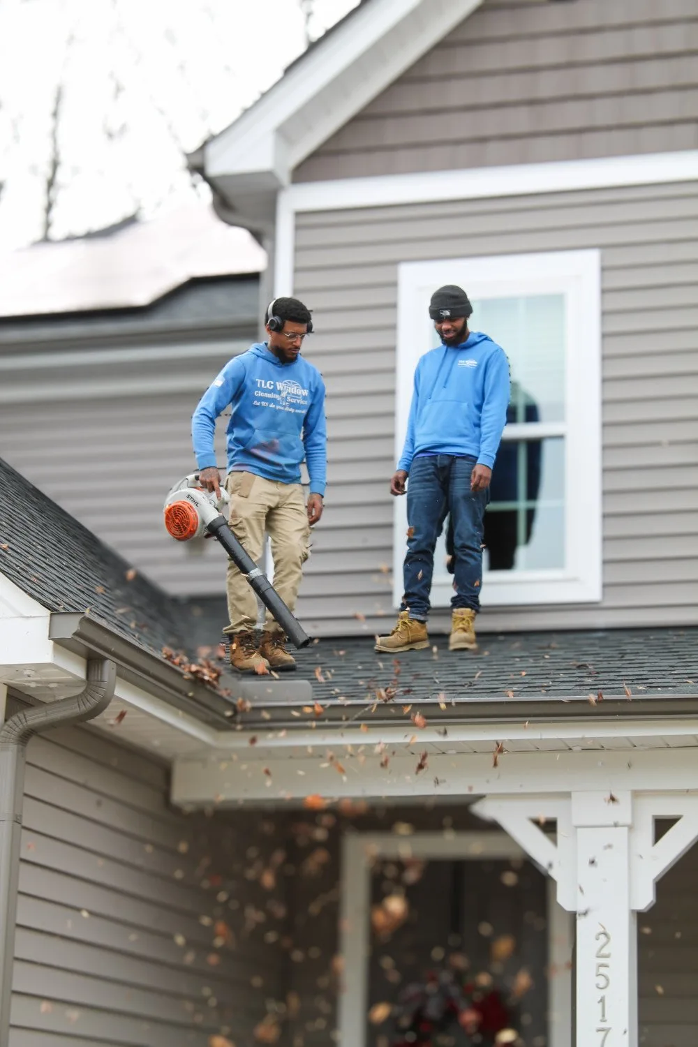 TLC team cleaning gutters on a NC home TLC Exterior Cleaning Services technician clearing fall leaves from a home’s gutters in the Triangle area of North Carolina